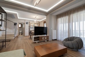 Ein modernes Wohnzimmer mit Flachbildfernseher, einer Couch und einer Treppe.