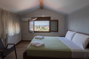 Ein Hotelzimmer mit Bett, Sessel, Fenster und Blick sowie einer Heizung.
