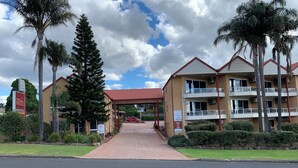 A motel with a red roof, multiple floors, and a covered walkway.