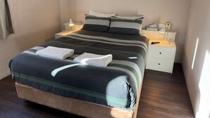 Een eenpersoonsbed met een gestreept dekbedovertrek, twee kussens, een nachtkastje met een lamp en een nachtkastje met een lamp.