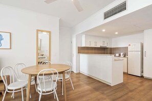 Eine moderne Küche mit weißen Schränken, einer Holzinsel und einem weißen Kühlschrank.