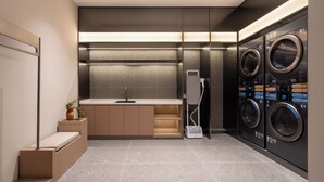 A modern laundry room with a built-in washer and dryer, a sink, and a small seating area. - homtel by PoLTTON（Xiamen Xiang'an Torch Industrial Park Branch） (Xiamen)