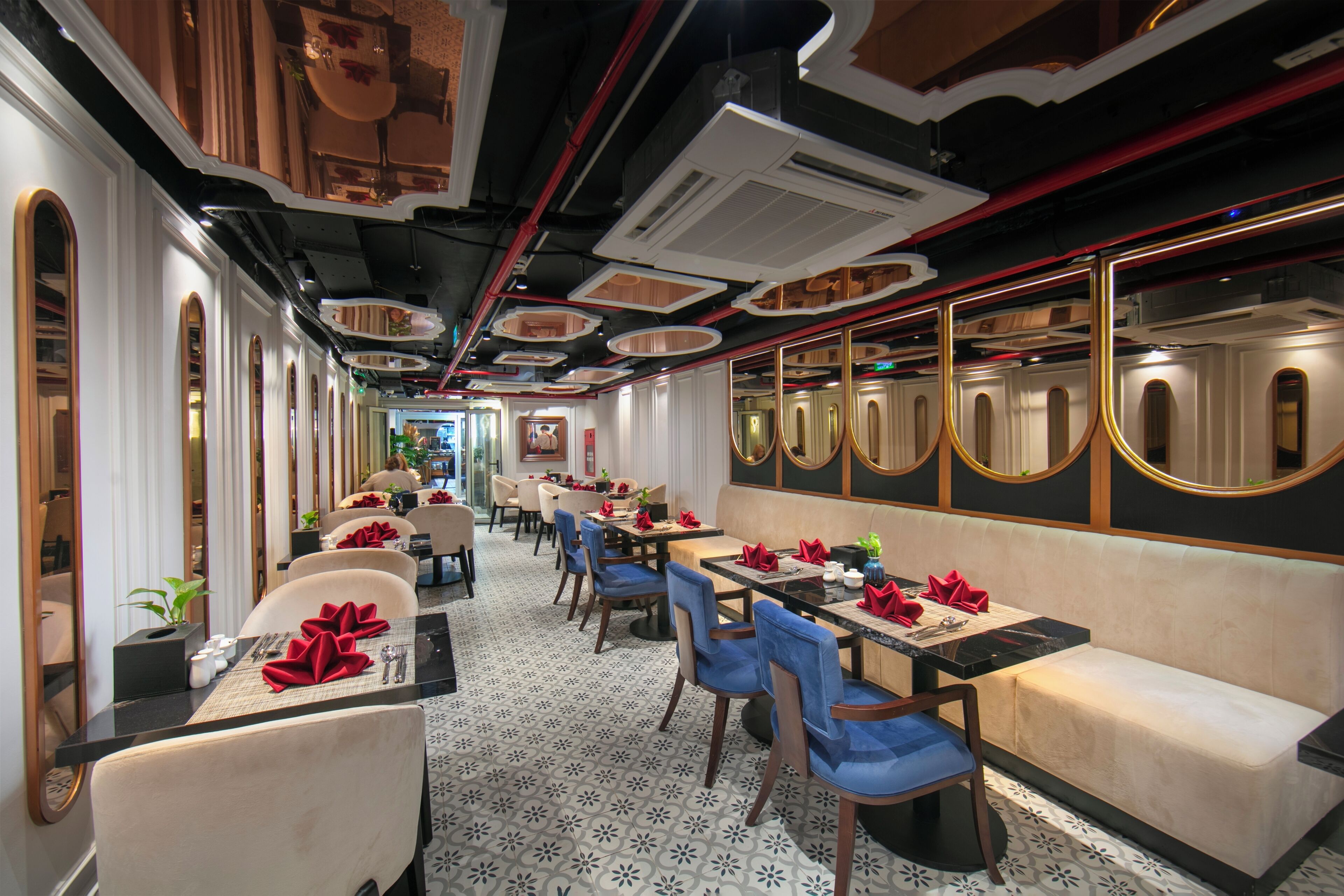 A restaurant with a long counter, multiple tables, and chairs.