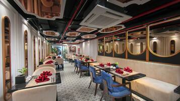 A restaurant with a long counter, multiple tables, and chairs.
