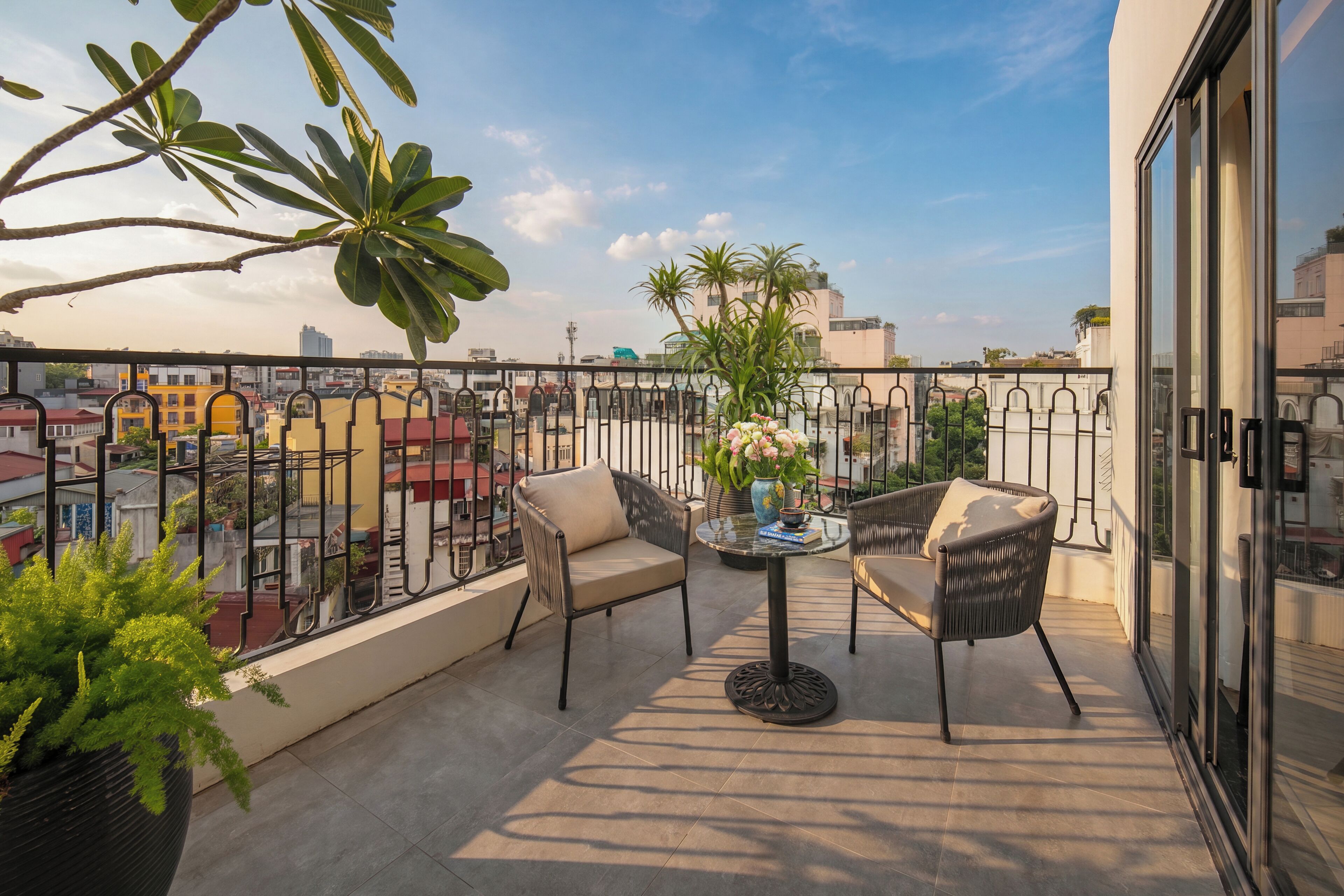 A balcony with two chairs, a table, and a potted plant.