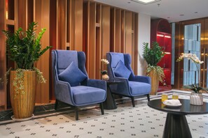 Un vestíbulo con dos sillones azules, una mesita y plantas decorativas.