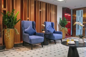 Eine Lobby mit zwei blauen Sesseln, einem kleinen Tisch und Zierpflanzen.