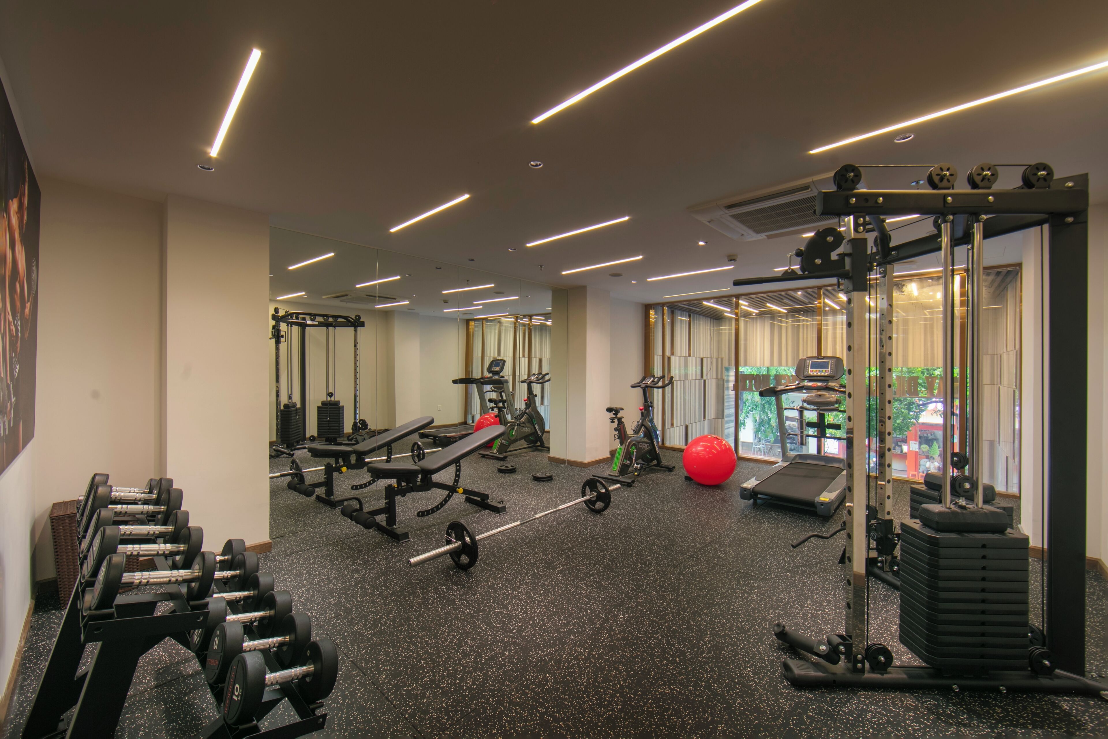 A gym with various exercise equipment, including dumbbells, a bench, and a treadmill.