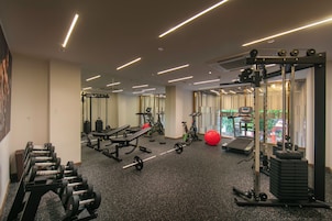 A gym with various exercise equipment, including dumbbells, a bench, and a treadmill.