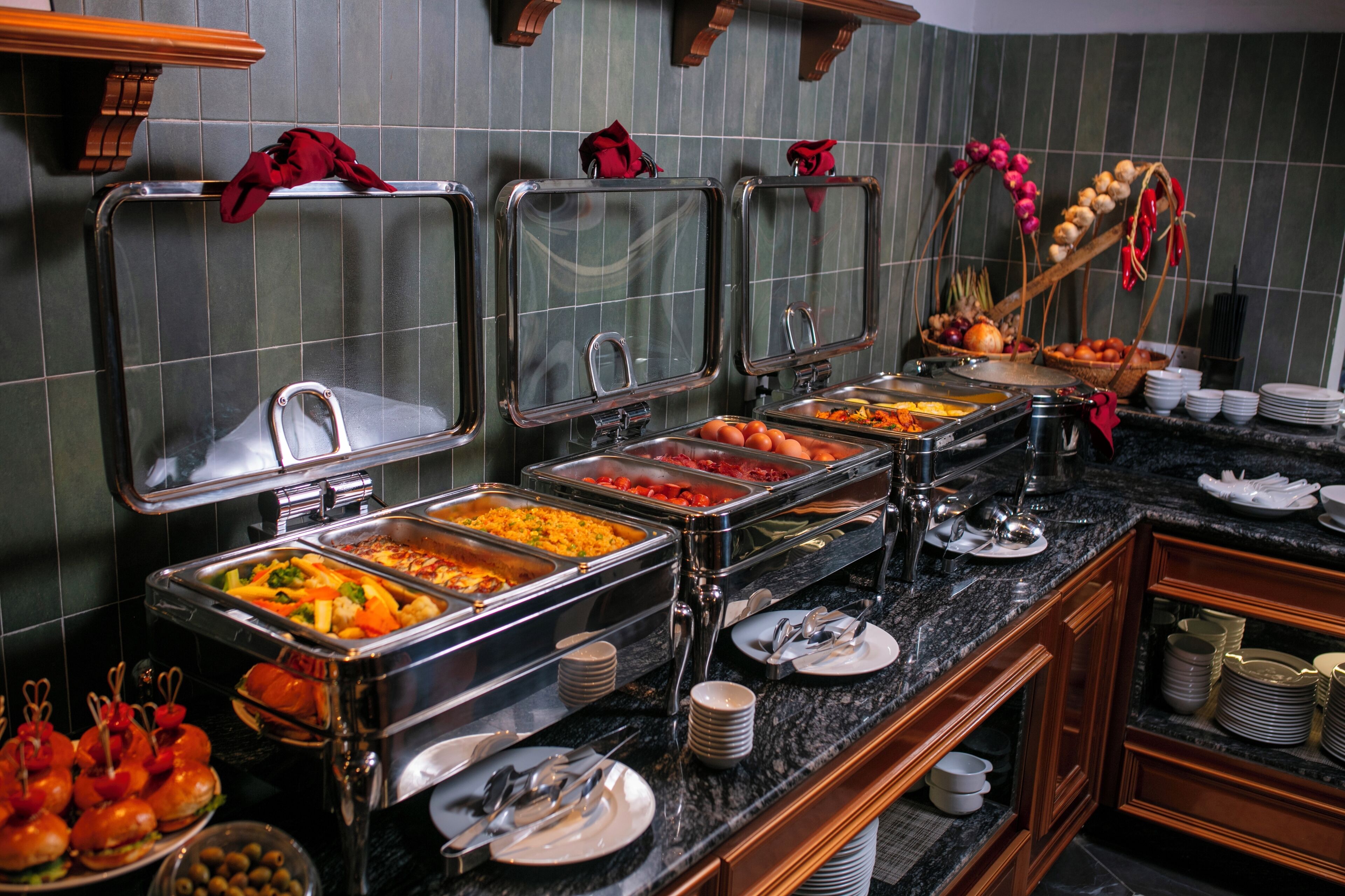 Montaje tipo bufé con varias estaciones de comida, que incluyen diversos platos, frutas y verduras.