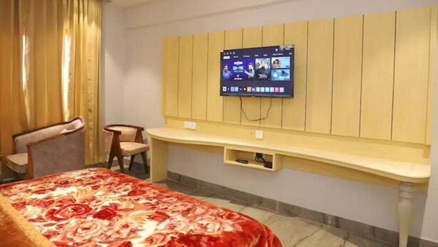 Ein Hotelzimmer mit einem Bett, einem an der Wand befestigten Fernseher, einem Schreibtisch und zwei Stühlen.