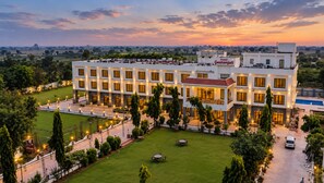 Un hotel con varios pisos, piscina y césped bien cuidado.