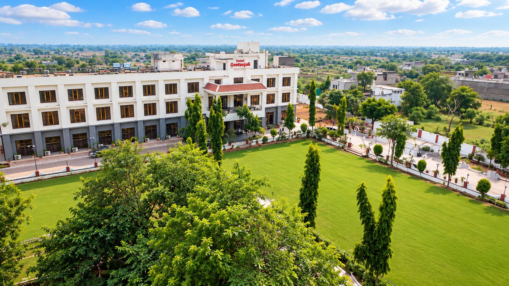 A hotel with a central courtyard, surrounded by trees and a view of the countryside.