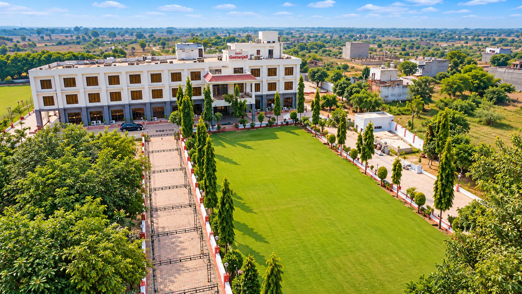 A large building with multiple floors, surrounded by a well-maintained lawn and trees.