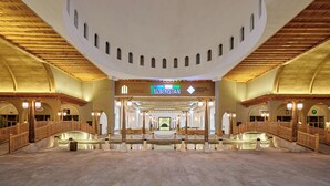 A spacious lobby with a high ceiling, a central staircase, and a sign indicating the location is in Uzbekistan.