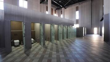 Een moderne toiletruimte met glazen scheidingswanden, een geruit vloertje en een hoge plafond.