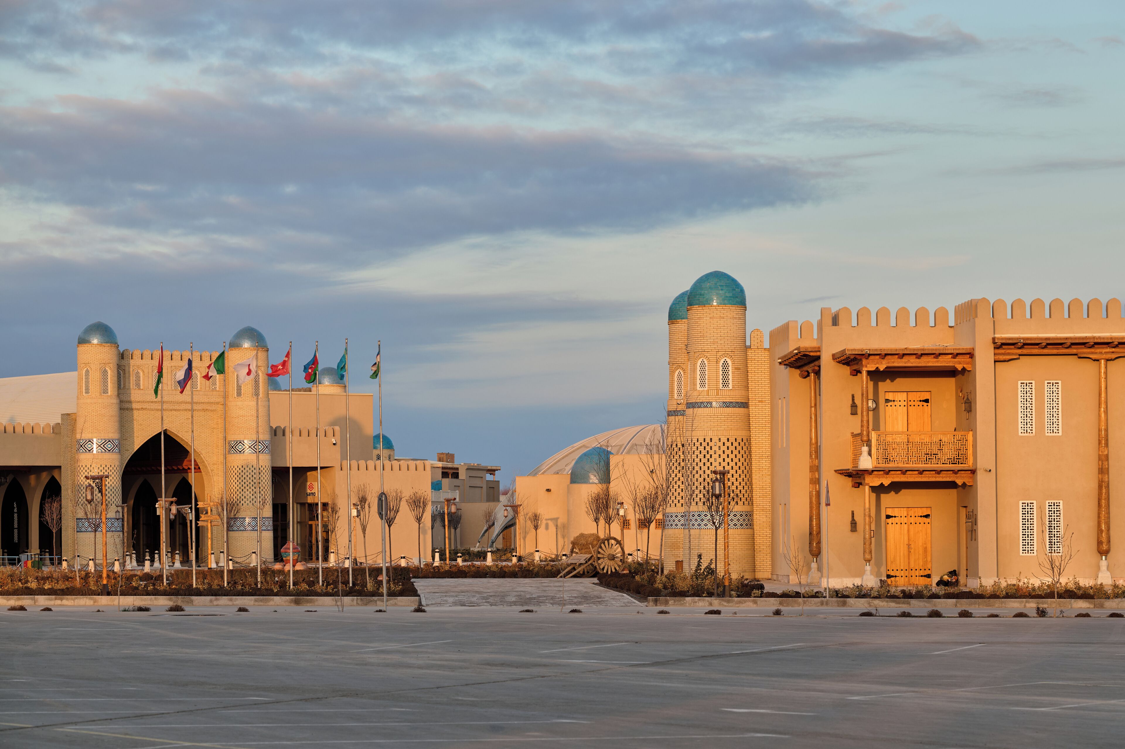 Una amplia plaza abierta con una mezquita que presenta cúpulas y minaretes, rodeada de edificios tradicionales con diseños intrincados.