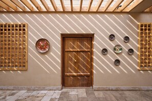 A wooden door with intricate patterns, a wall with a decorative plate, and a series of small plates on the wall. - Arda Angariki (Khiva)