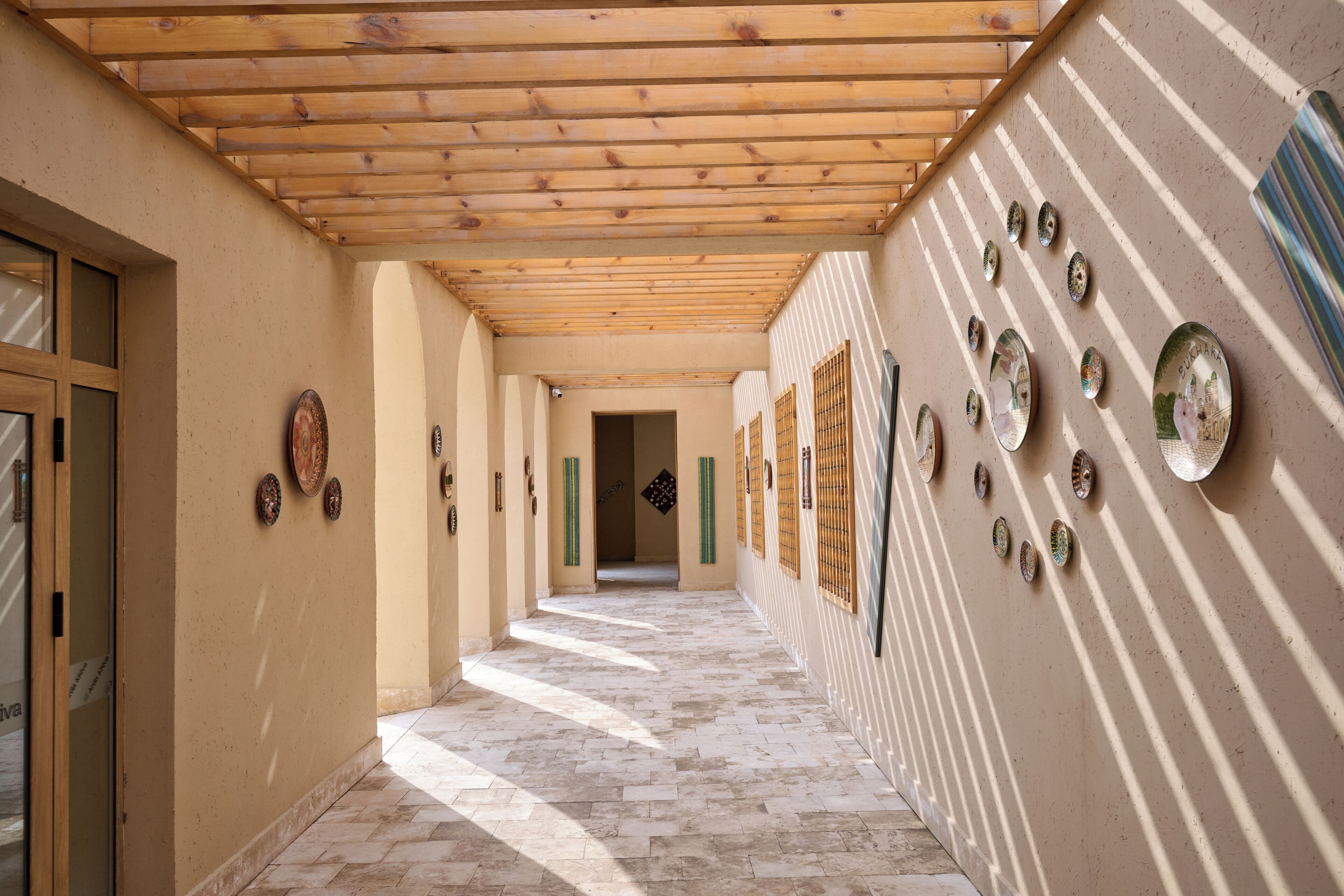 Un pasillo con techo de madera, baldosas con diseño y placas decorativas en las paredes.