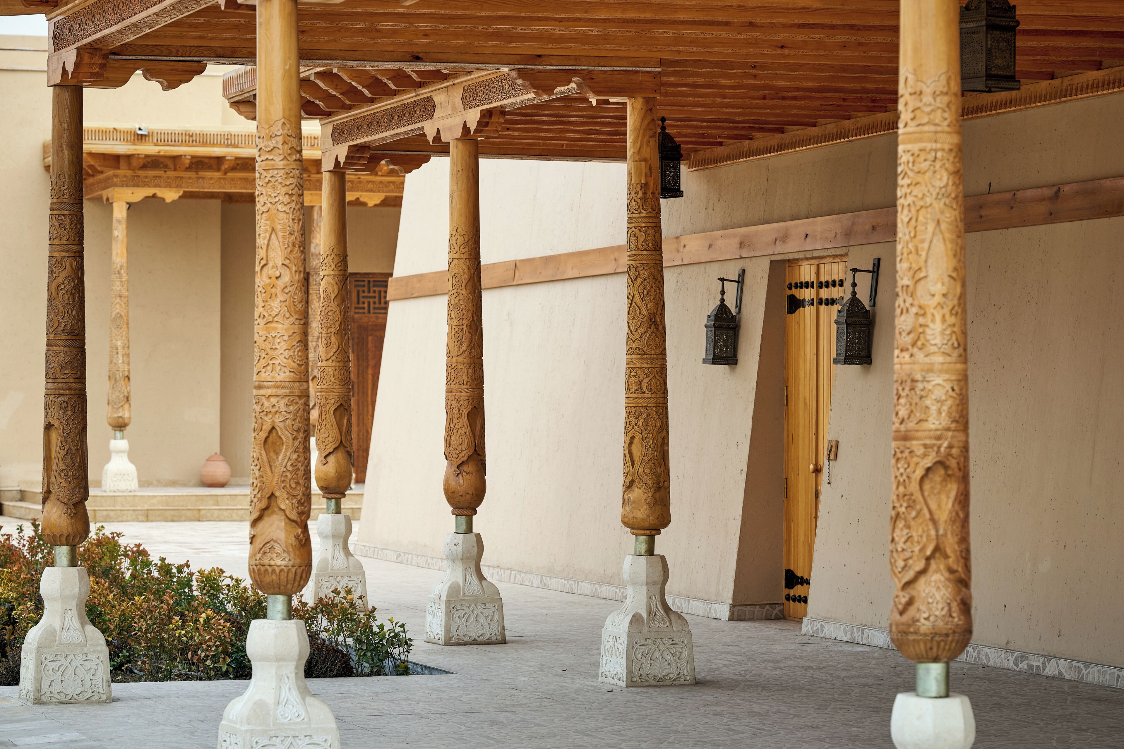 Un espacio al aire libre techado con columnas de madera ornamentadas y piso de baldosas.