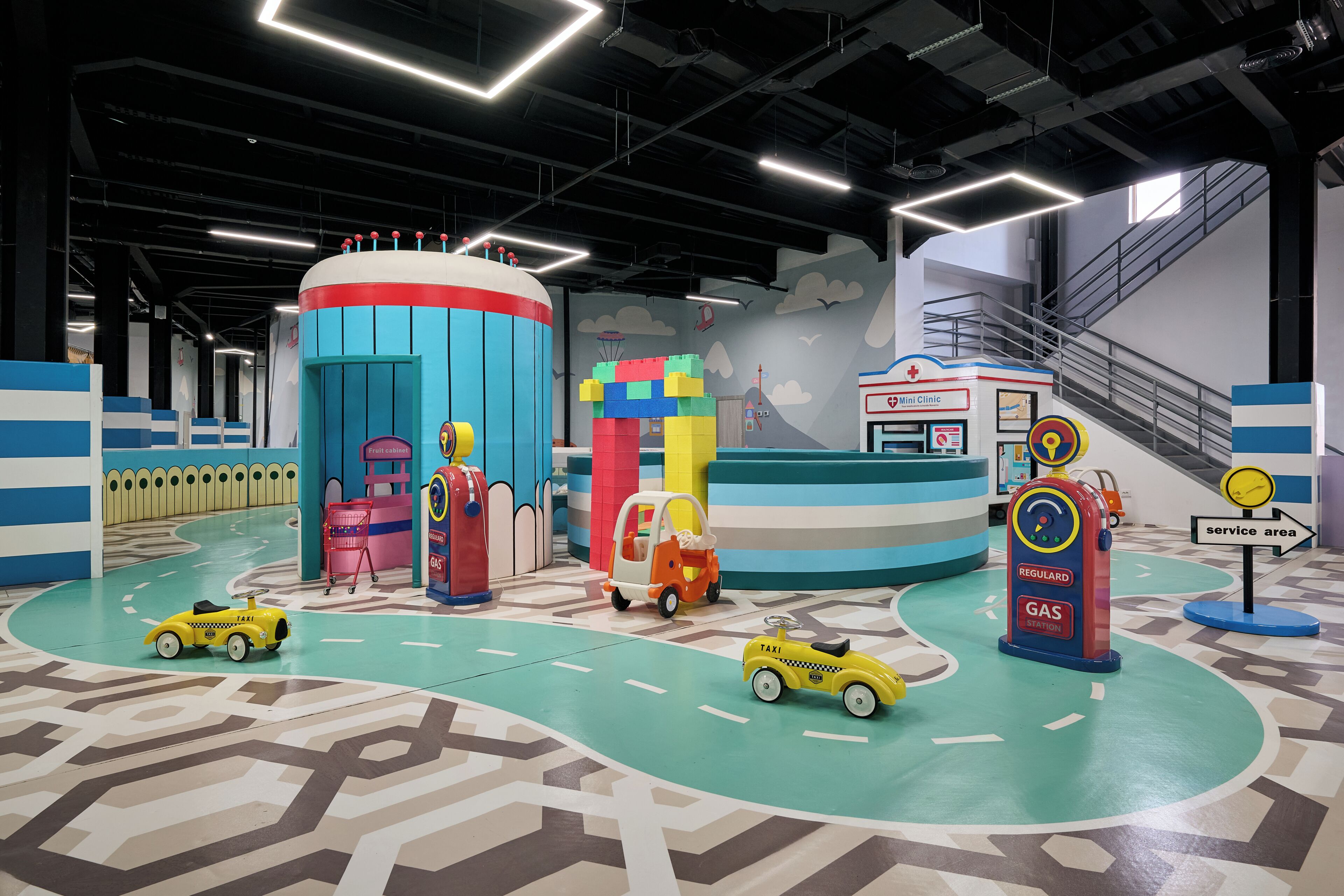 Un área de juegos con coches de juguete, una clínica infantil y una gasolinera.