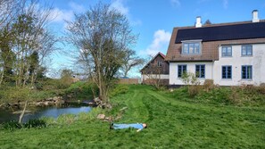 A house with a grassy yard and a pond.