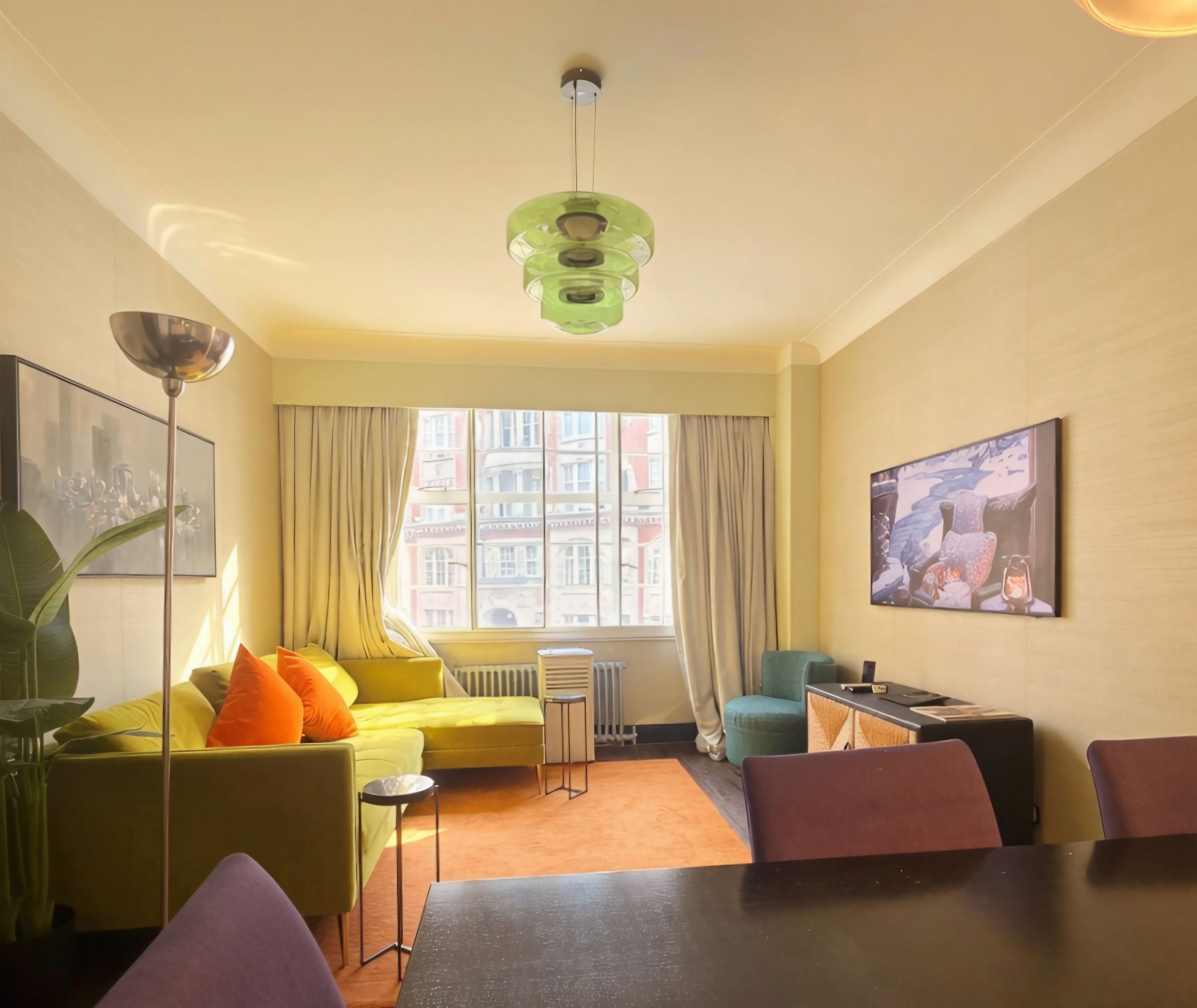 A modern living room with a sofa, a dining table, and a large window.