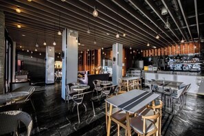 An indoor restaurant with tables and chairs, a bar area, and a wet floor. - Dali Shuanglang Junlan Tangsu (Dali City)