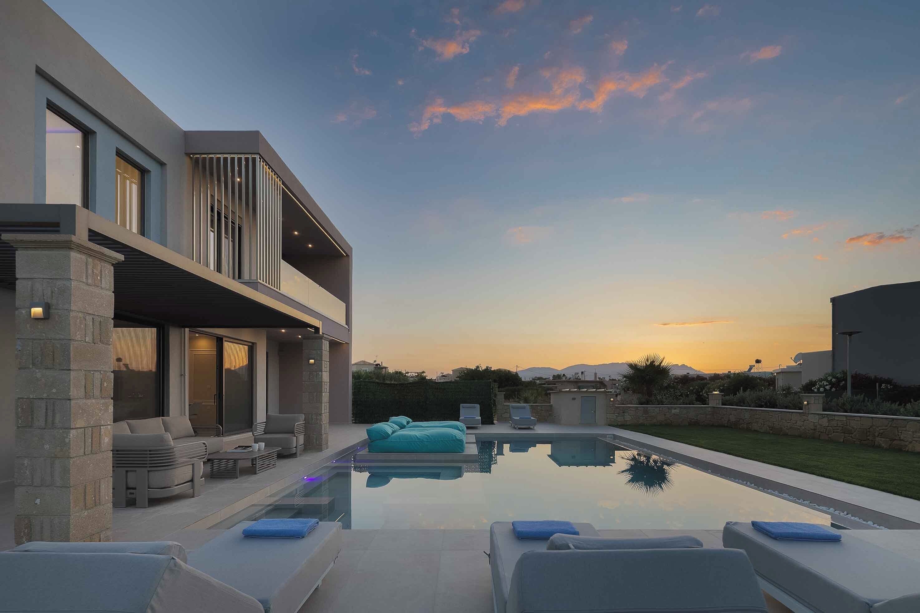 Ein modernes Haus mit Swimmingpool, Sitzgelegenheit im Freien und Blick auf den Sonnenuntergang.