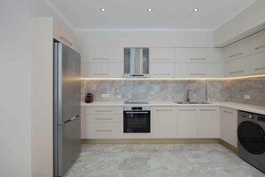 A modern kitchen with a stainless steel refrigerator, built-in oven, and washing machine. - Atriora Luxury Villa | Private Pool & 150m to sea! (Kissamos)