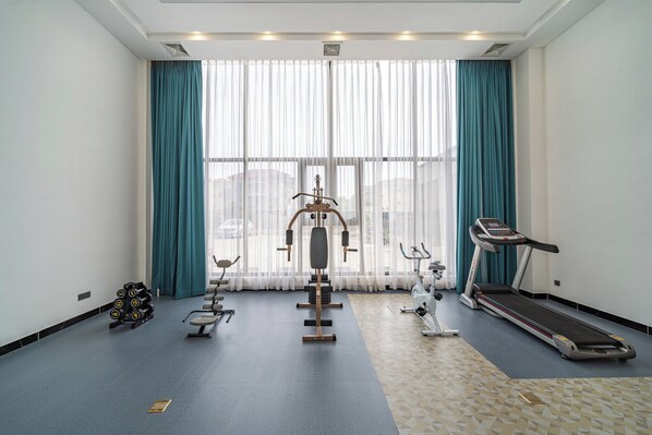 A gym with exercise equipment, a treadmill, and a patterned floor.