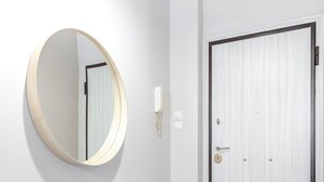 Ein Flur mit einem runden Spiegel an der Wand, einer Tür mit Knauf und einem Lichtschalter.
