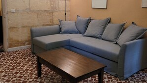 Ein Wohnzimmer mit einem Ecksofa, einem Couchtisch, einer Karte an der Wand und einer Stehlampe.