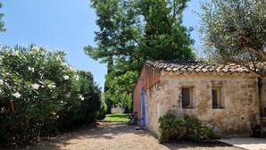 Ein rustikales Steinhaus mit Ziegeldach, einem Schotterweg und üppiger Vegetation.