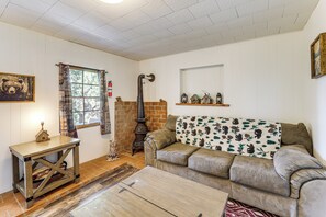 Ein Wohnzimmer mit einer Couch, einem Tisch, einem Kamin und einem Fenster mit Vorhängen.