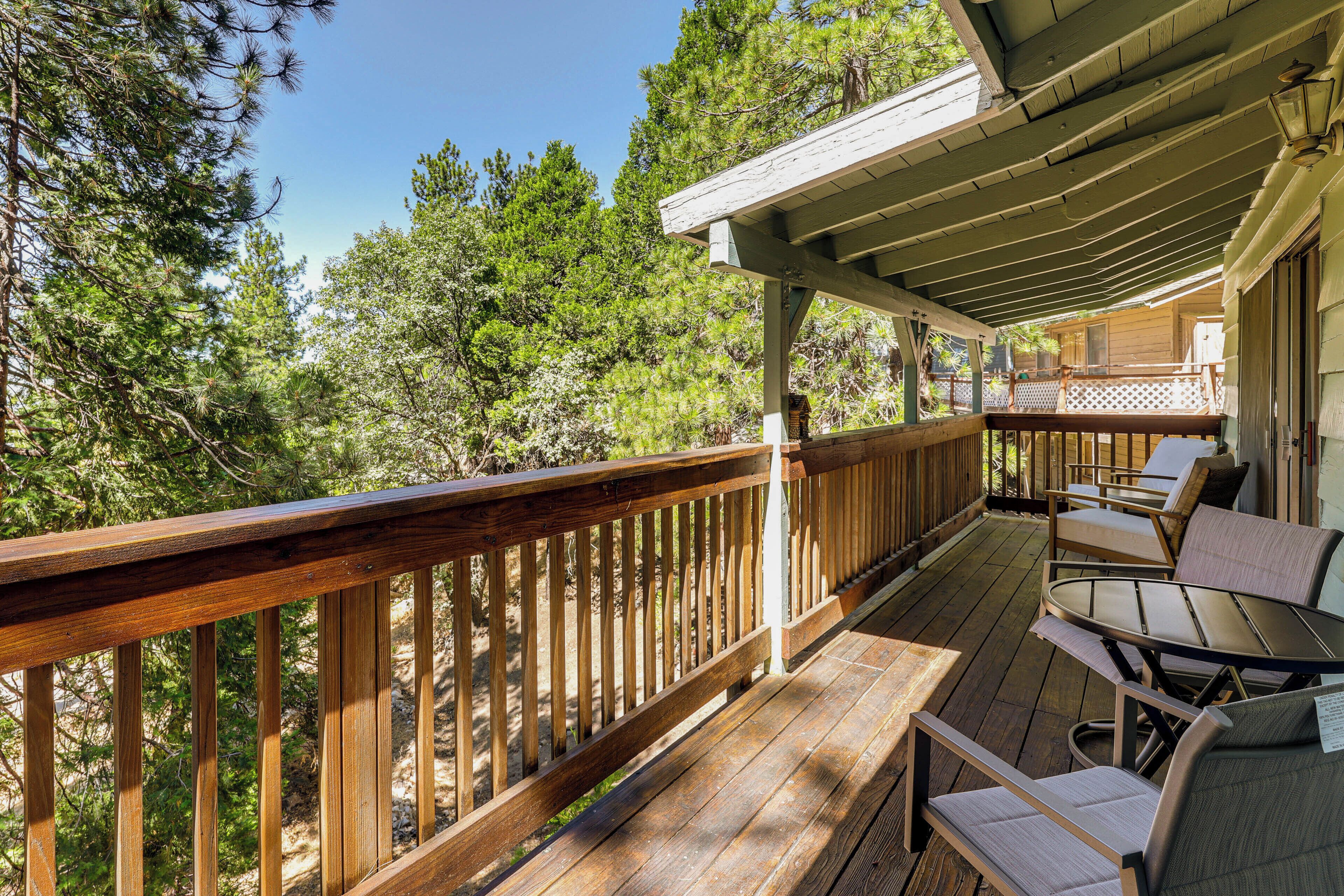 A wooden deck with outdoor furniture, surrounded by trees.