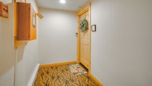 A hallway with a wooden door, a fire alarm, and a patterned rug on the floor. - Keystone Lakefront Retreat! Pool & Hot Tub Access (Keystone)