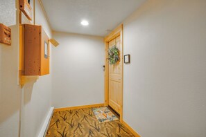 A hallway with a wooden door, a fire alarm, and a patterned rug on the floor. - Keystone Lakefront Retreat! Pool & Hot Tub Access (Keystone)