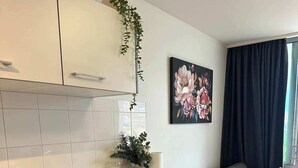 Ett modernt kök med en bänkskiva, en vattenkokare, en brödrost och en växt. Det finns en soffa med en kudde och en tavla på väggen.