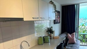 Ett modernt kök med en inbyggd ugn, en diskho och en matplats med en soffa och stolar.