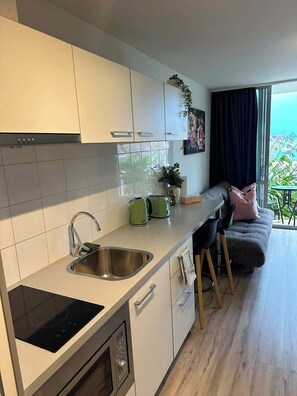 Eine moderne Küche mit Backofen, Spüle und Essbereich mit Sofa und Stühlen.