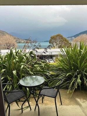 Patio esterno con tavolo e sedie, affacciato su un corpo d'acqua e colline.