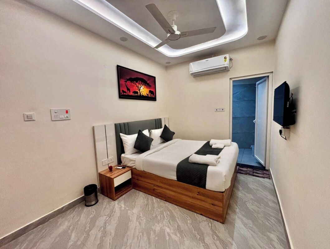 Una habitación de hotel moderna con cama, mesita de noche, televisor montado en la pared y aire acondicionado.