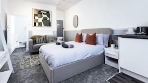 Een moderne hotelkamer met een bed, nachtkastje en een bureau met stoel.