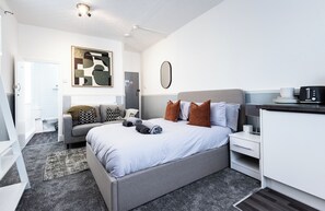 Ein modernes Hotelzimmer mit Bett, Nachttisch und Schreibtisch mit Stuhl.