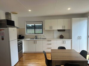 Een moderne keuken met witte kastjes, een ingebouwde oven, een magnetron en een raam met uitzicht.