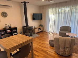 Een woonkamer met een houten tafel, een bank, een televisie en een open haard.