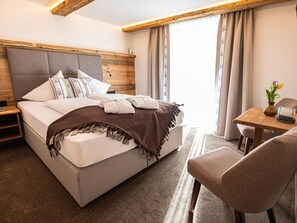 Ein Schlafzimmer mit Bett, Nachttisch, Stuhl und einem Fenster mit Vorhängen.