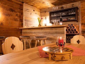 Ein Holzinnenraum mit Barbereich, Holzsesseln, einem Tisch mit Schachbrett und einem Weinkühlschrank.