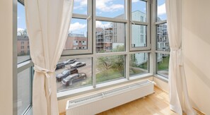 A room with a large window overlooking a parking area and buildings.